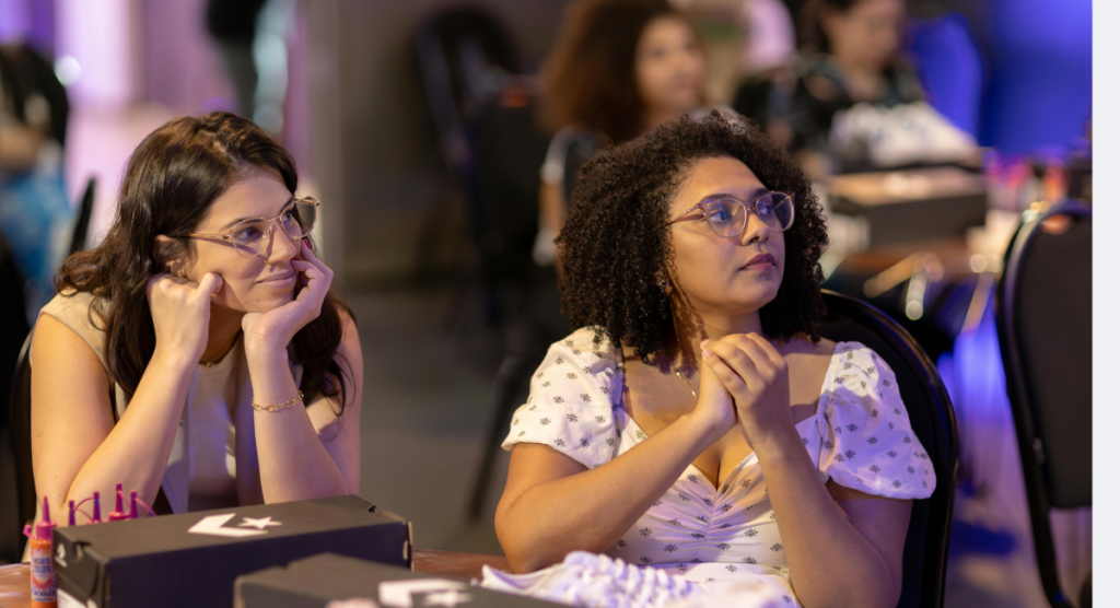 Two women focused on a presentation, illustrating how a strong before-the-fold story captures attention early in the user journey.