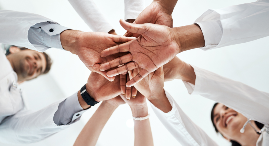 Team joining hands in a circle to symbolize the promise a homepage must make above the fold to earn user trust and attention.