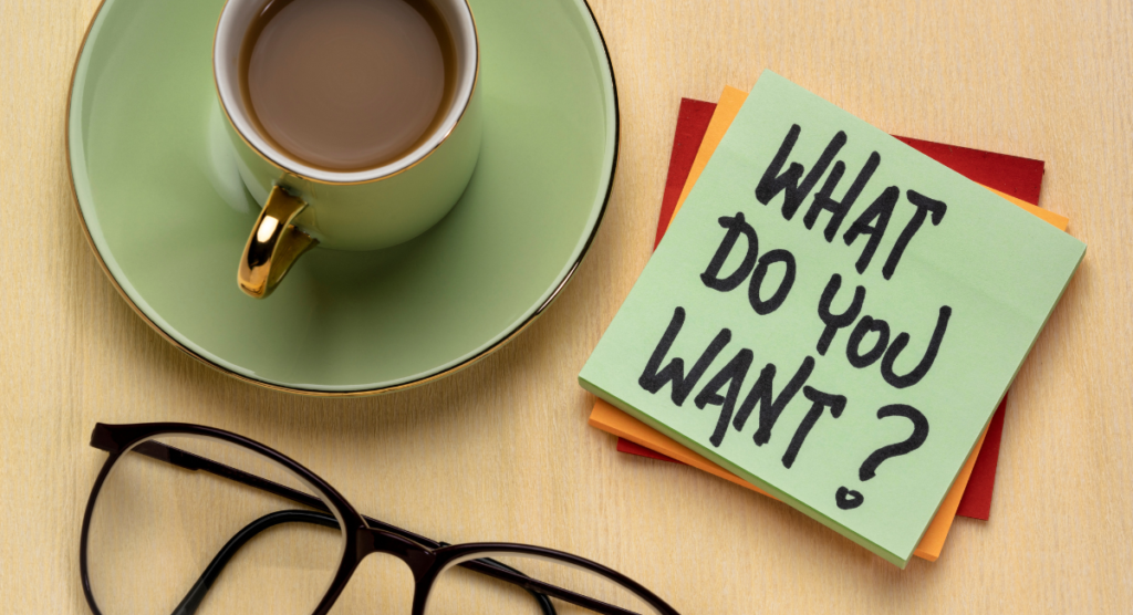 Sticky note asking “What do you want?” beside coffee and glasses, highlighting the need to understand user motivations before change.
