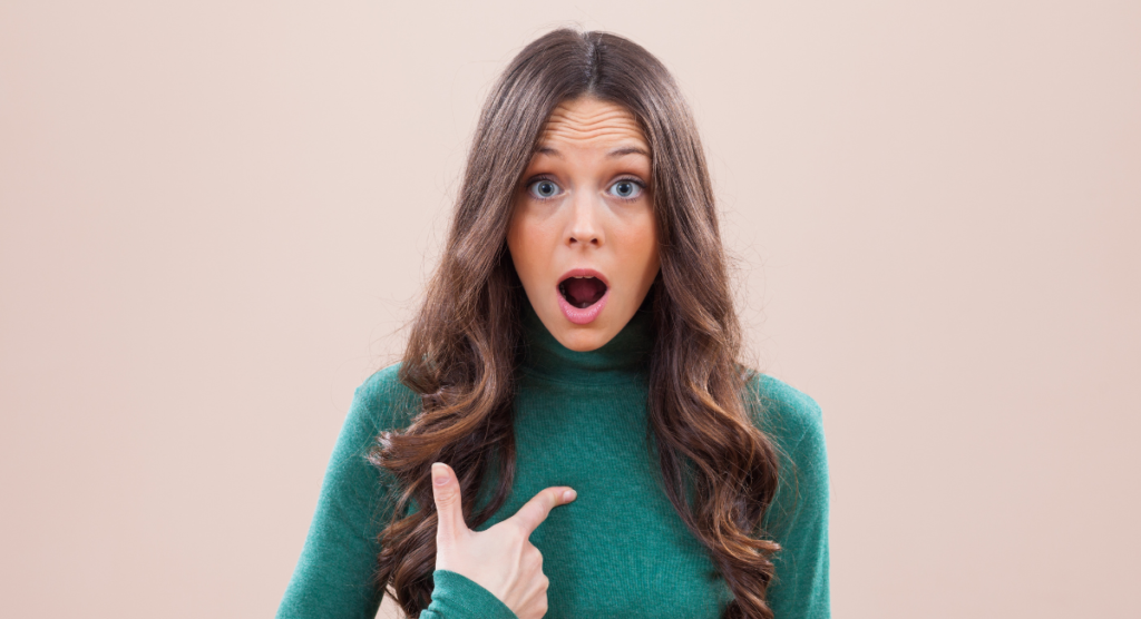 Woman pointing to herself with a surprised expression, reflecting a visitor’s instinctive question of whether a landing page is meant for them.