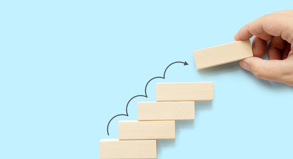 Hand stacking wooden blocks upward, illustrating how clear product stories reveal a simple path from user pain to progress.