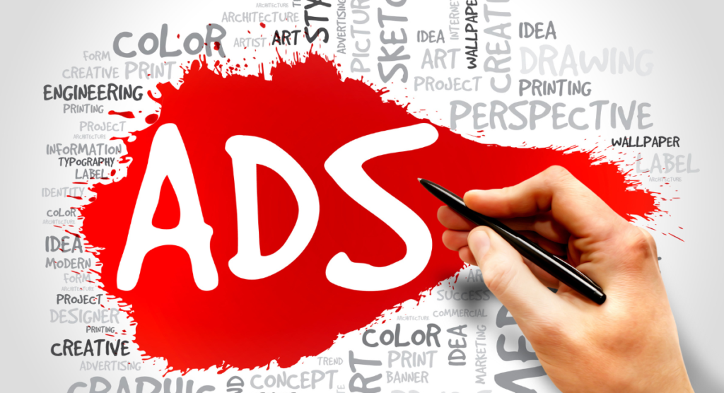 Hand writing “ADS” on a red splash background surrounded by marketing and creative-related words.