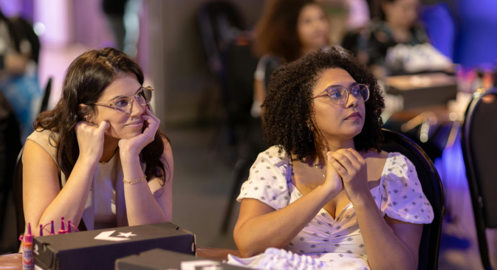 Two attendees listen intently during a presentation, illustrating how engaged users become when a SaaS product story clearly reveals its value.