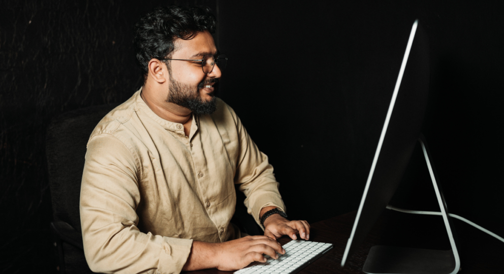 A founder works at a computer with a focused, confident smile, illustrating how a clear personal story drives the purpose and direction behind a SaaS product.